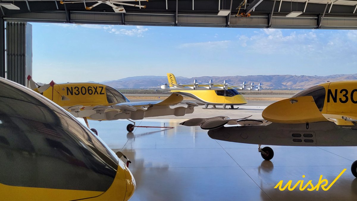 4 yellow wisk evtol in a hangar overlooking hills